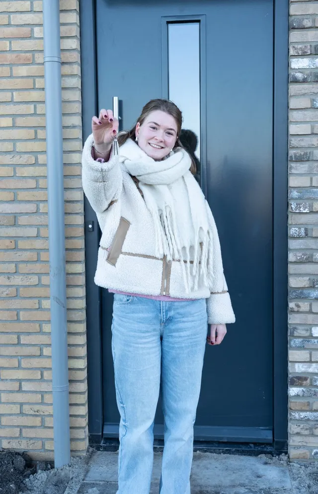 Bewoner met de sleutel van haar nieuwbouwwoning